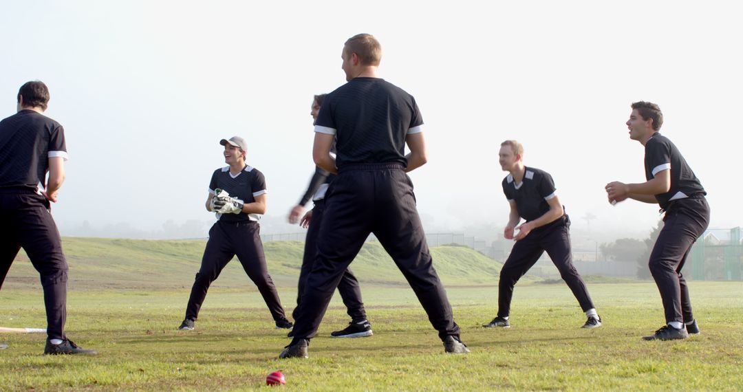 Athletes Practicing on Foggy Cricket Field with Focus on Teamwork
