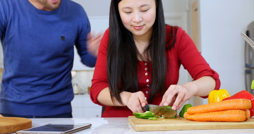 Young Asian Woman Chopping Vegetables in Modern Kitchen with Partner - Free Images, Stock Photos and Pictures on Pikwizard.com