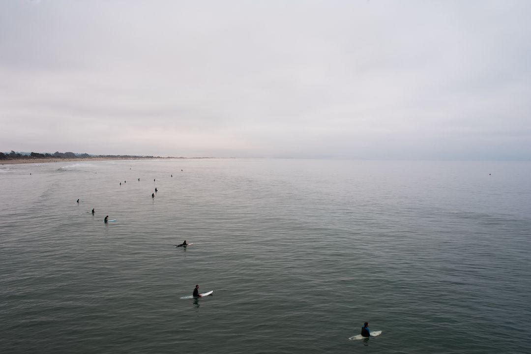 Group of Surfers Waiting for Waves in Calm Ocean on Cloudy Day - Free Images, Stock Photos and Pictures on Pikwizard.com