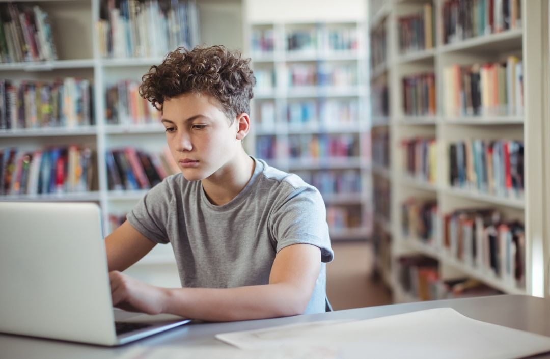 Teenage Boy Studying with Laptop in Public Library