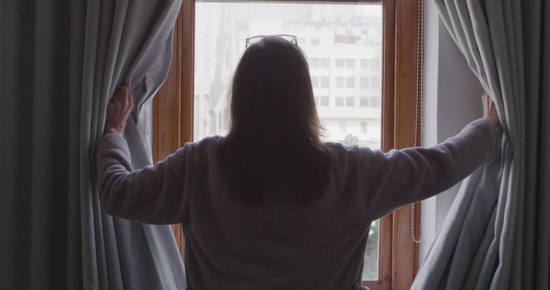 Woman Opening Curtains to Morning Light in City Apartment - Free Images, Stock Photos and Pictures on Pikwizard.com