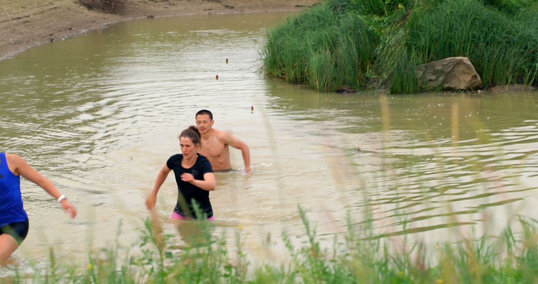 Participants Running Through Muddy Water at Outdoor Obstacle Race - Free Images, Stock Photos and Pictures on Pikwizard.com