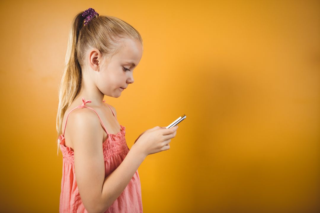 Young Girl Using Smartphone Against Orange Background - Free Images, Stock Photos and Pictures on Pikwizard.com