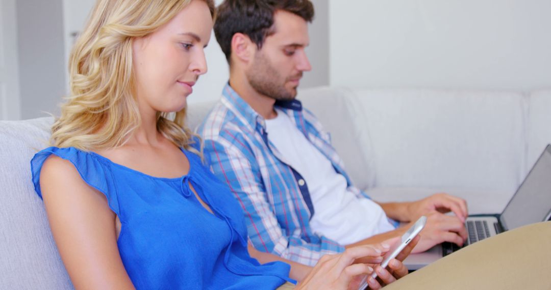 Couple Using Digital Devices on Home Sofa Relaxing