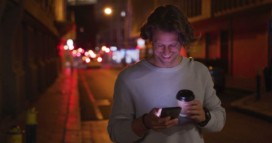 Man Walking at Night Using Smartphone and Holding Coffee - Free Images, Stock Photos and Pictures on Pikwizard.com