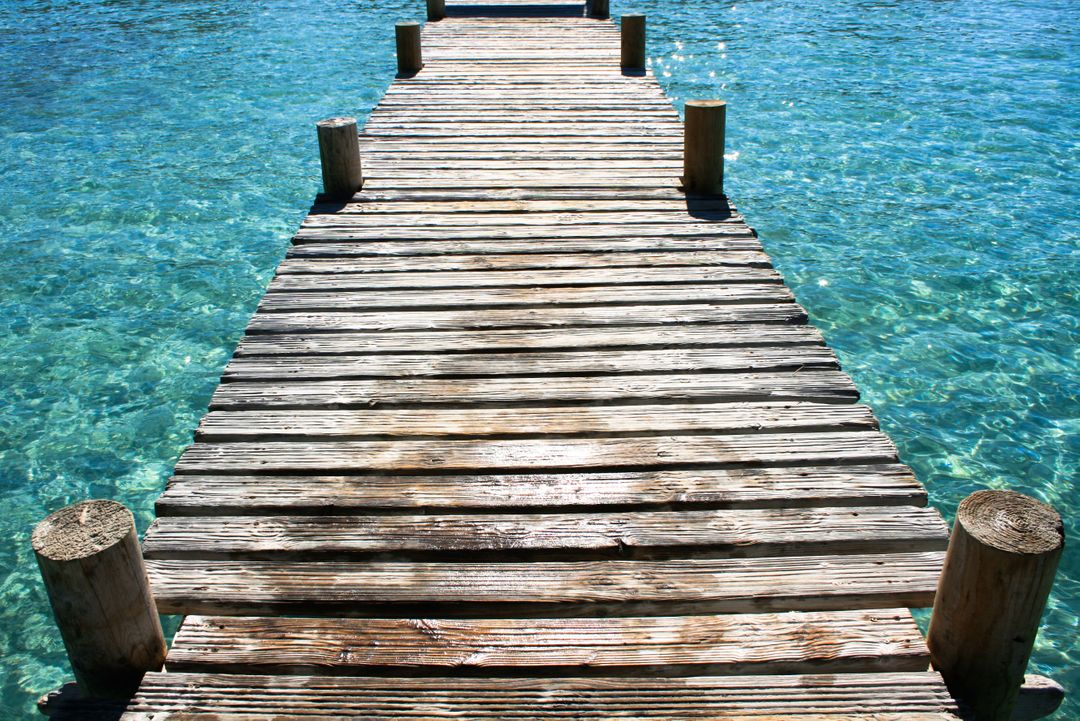 Wooden Pier Extending Over Crystal Clear Blue Water - Free Images, Stock Photos and Pictures on Pikwizard.com