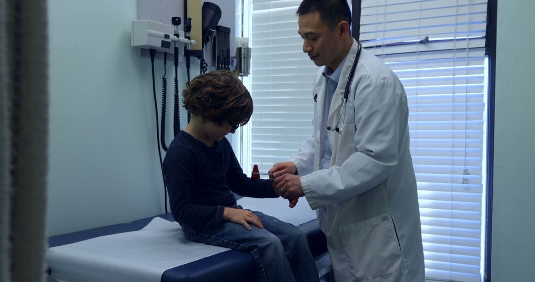 Pediatrician Examining Young Boy's Wrist In Medical Clinic - Free Images, Stock Photos and Pictures on Pikwizard.com