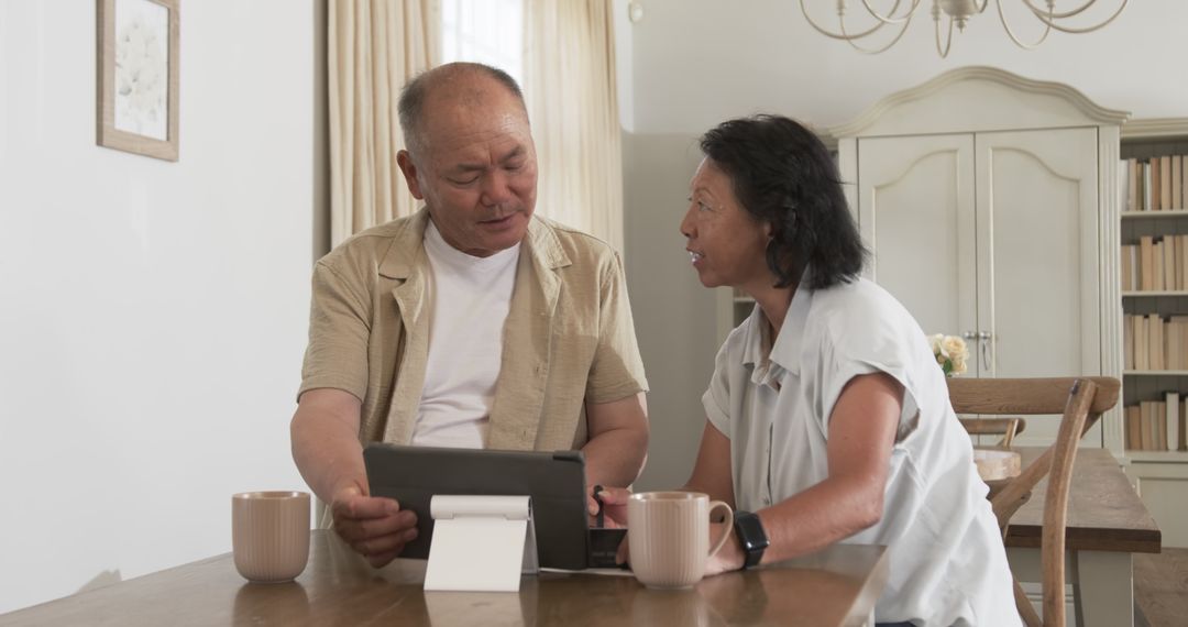 Senior Asian Couple Using Tablet for Financial Planning at Home