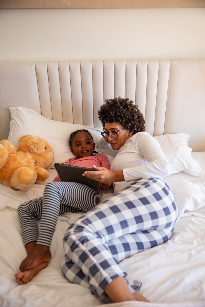 Mother and Daughter Bonding with Tablet on Bedroom Bed