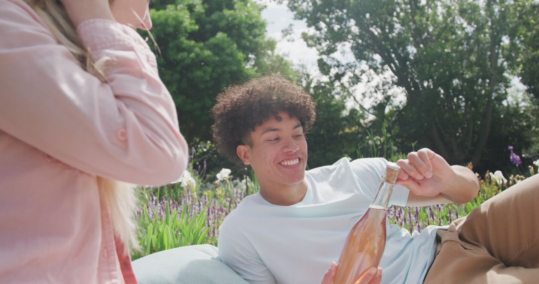 Happy Couple Enjoying Picnic with Sparkling Drink Outdoors