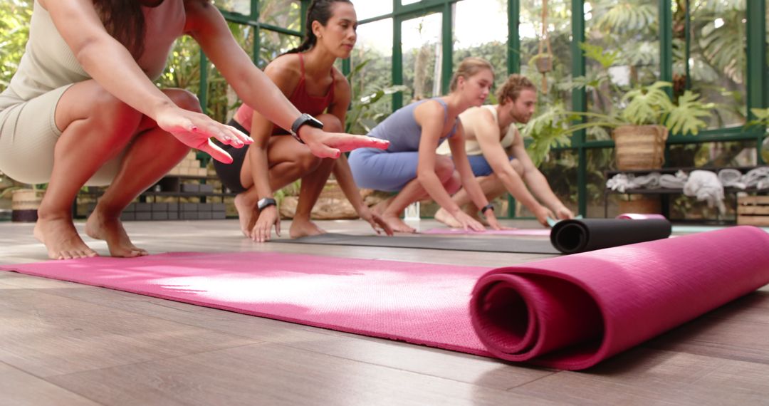 Diverse Fit Group Preparing Yoga Mats in Tranquil Glass Studio