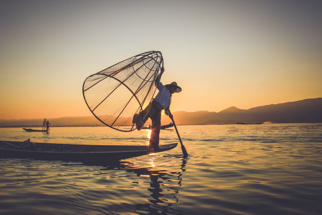 Traditional Fisherman Balancing on Canoe at Sunrise - Free Images, Stock Photos and Pictures on Pikwizard.com