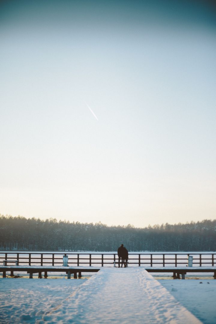 Couple Walking on Winter Snow-Covered Pier at Sunrise - Free Images, Stock Photos and Pictures on Pikwizard.com