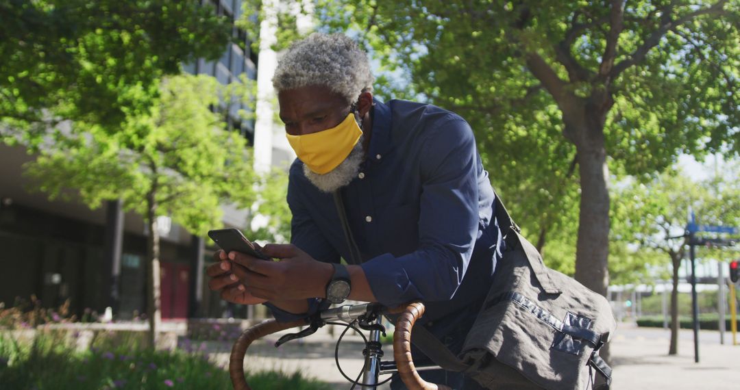 Senior Man in Face Mask Using Phone While Urban Biking - Free Images, Stock Photos and Pictures on Pikwizard.com