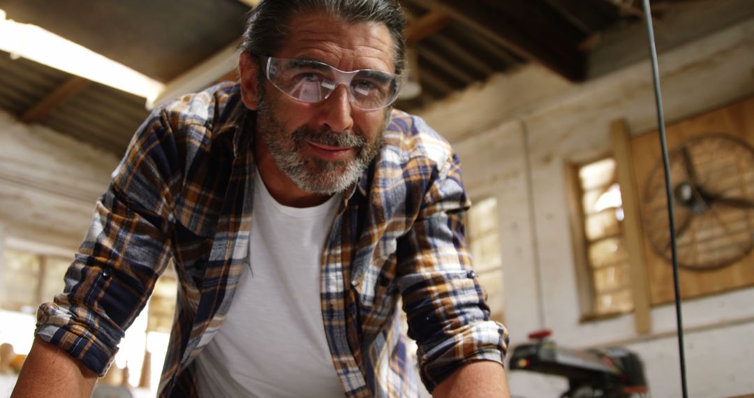 Confident Male Carpenter Wearing Safety Glasses in Workshop - Free Images, Stock Photos and Pictures on Pikwizard.com