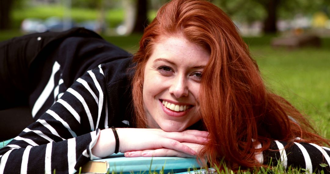 Smiling Woman with Red Hair Relaxing on Grass - Free Images, Stock Photos and Pictures on Pikwizard.com