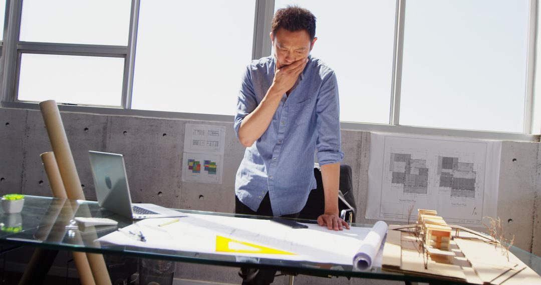 Asian Architect Analyzing Blueprint in Modern Office