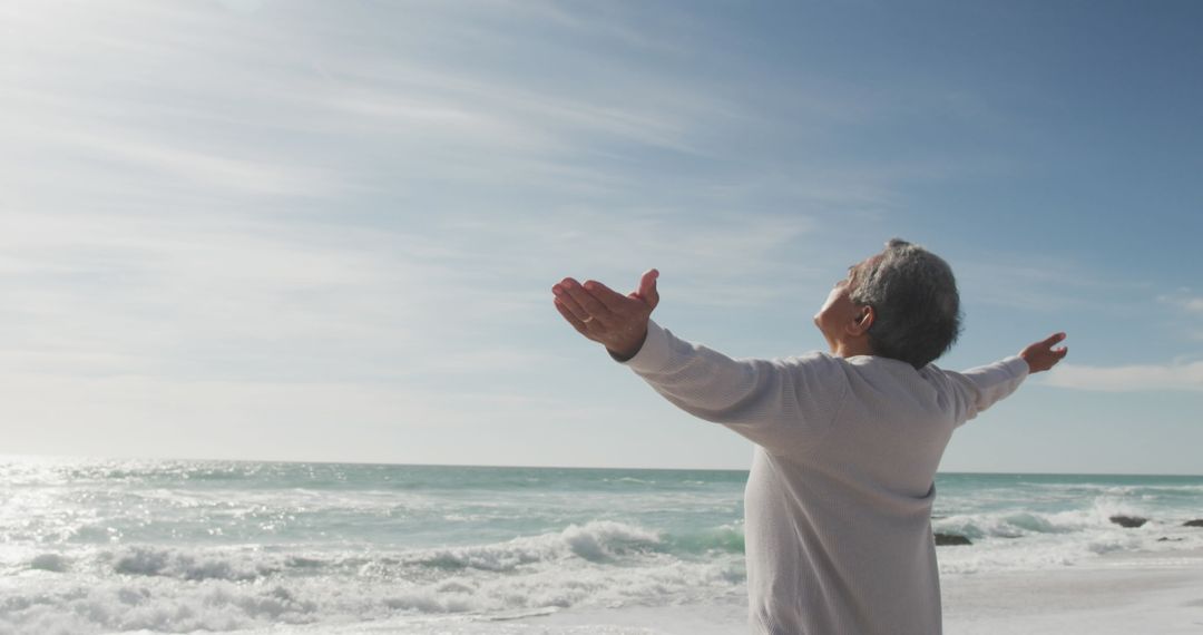 Senior Man Embracing Freedom at Ocean Shoreline