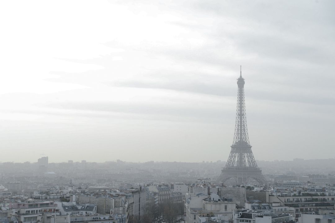 Eiffel Tower amidst hazy Paris skyline on a cloudy day - Free Images, Stock Photos and Pictures on Pikwizard.com