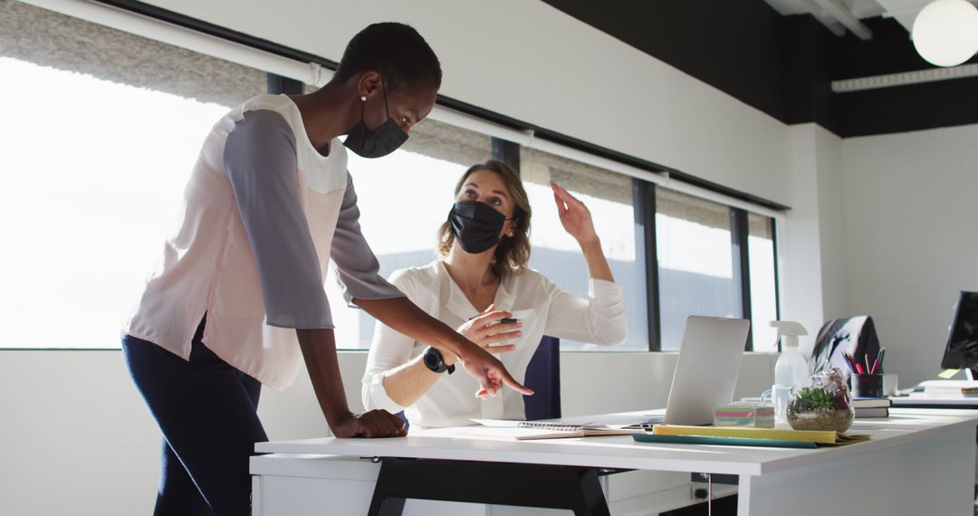 Diverse Colleagues Collaborating with Laptops in Modern Office