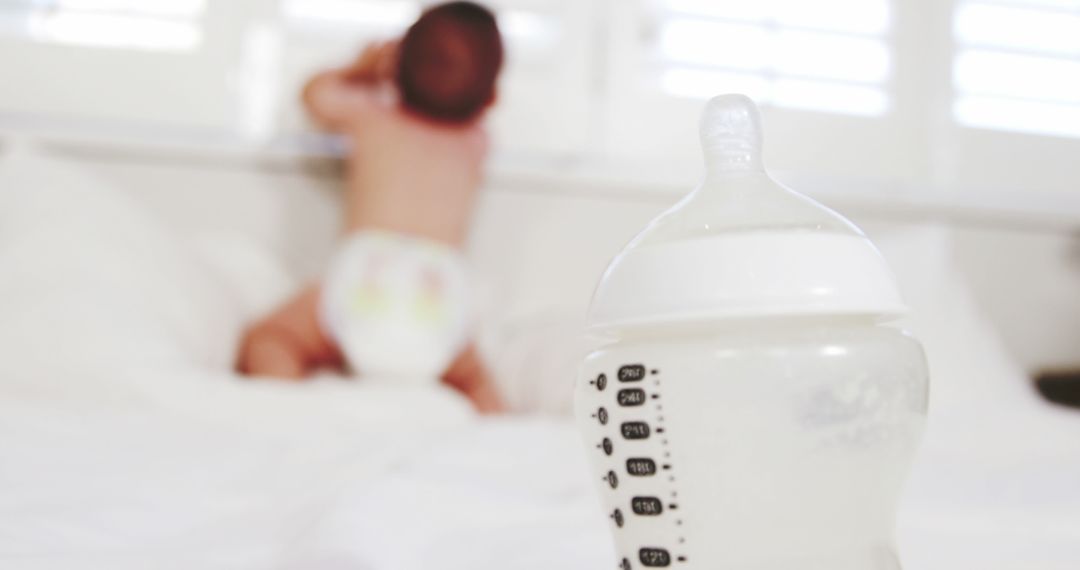 Baby Crawling with Milk Bottle in Foreground on Bed - Free Images, Stock Photos and Pictures on Pikwizard.com