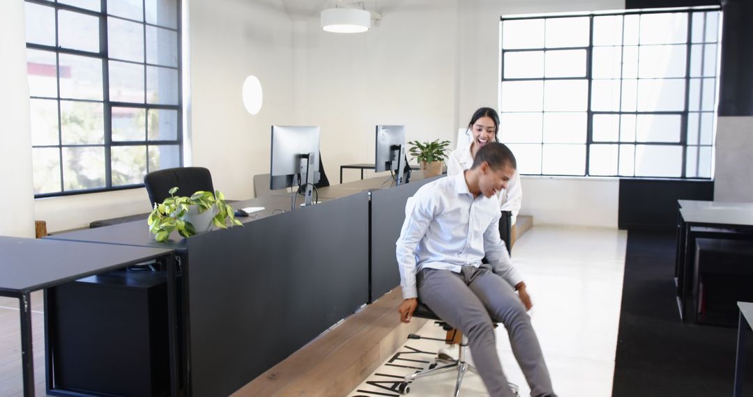 Two Colleagues Having Fun in Modern Office with Rolling Chair
