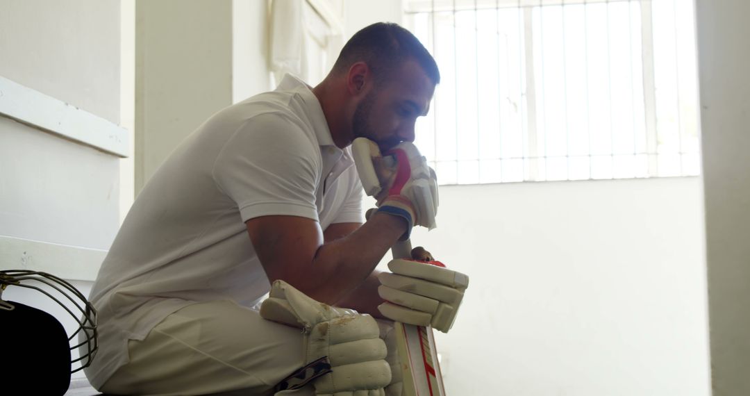 Cricketer Sitting in White Locker Room Reflecting with Gear - Free Images, Stock Photos and Pictures on Pikwizard.com