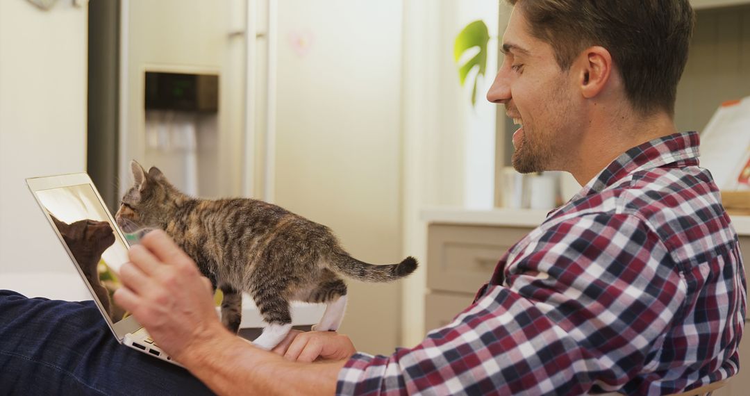 Man Smiling at Cat on Laptop at Home