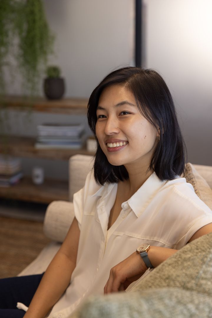 Smiling Asian Woman Relaxing on Cozy Sofa in Modern Lounge