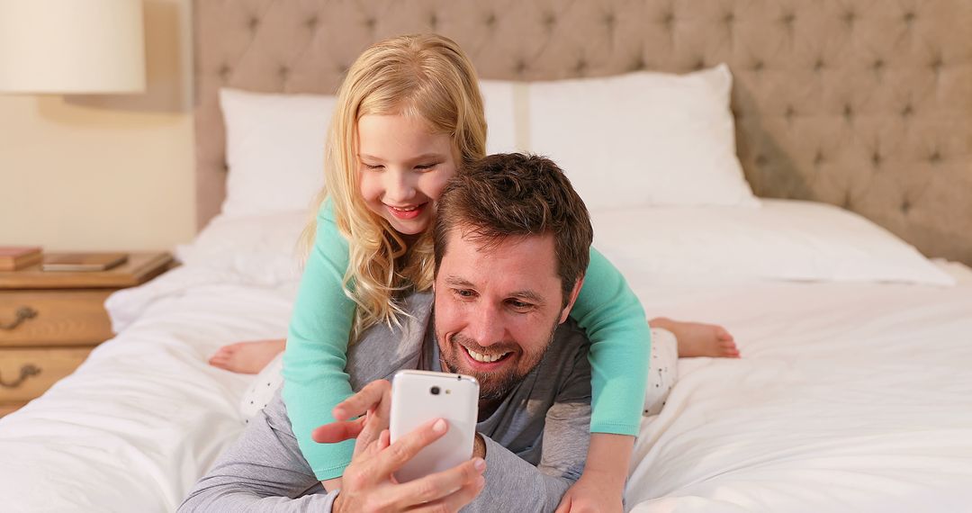 Father and Daughter Using Smartphone on Bed - Free Images, Stock Photos and Pictures on Pikwizard.com