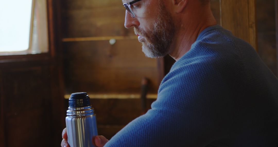 Man in Cabin with Thermos, Contemplating Indoor Comfort - Free Images, Stock Photos and Pictures on Pikwizard.com