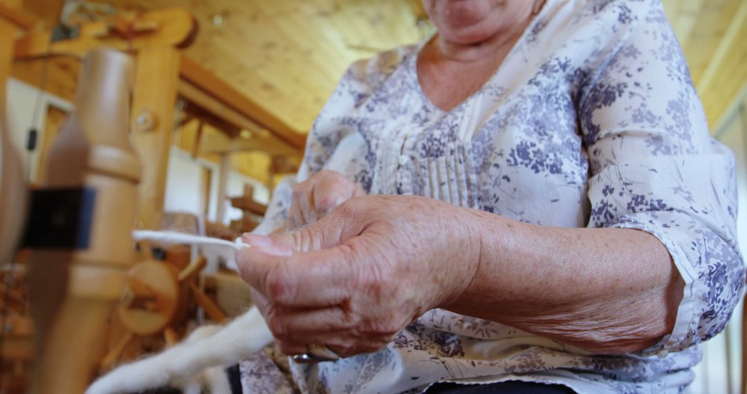 Senior Caucasian woman spins yarn on an old-fashioned spinning wheel at home - Free Images, Stock Photos and Pictures on Pikwizard.com