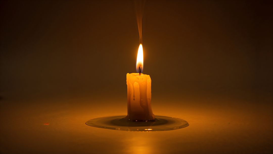 Glowing Candle with Melted Wax Pool on Dark Surface