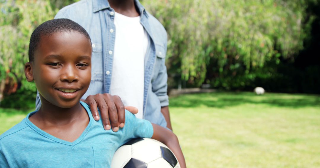 Smiling Boy Holding Soccer Ball With Father Outdoors - Free Images, Stock Photos and Pictures on Pikwizard.com