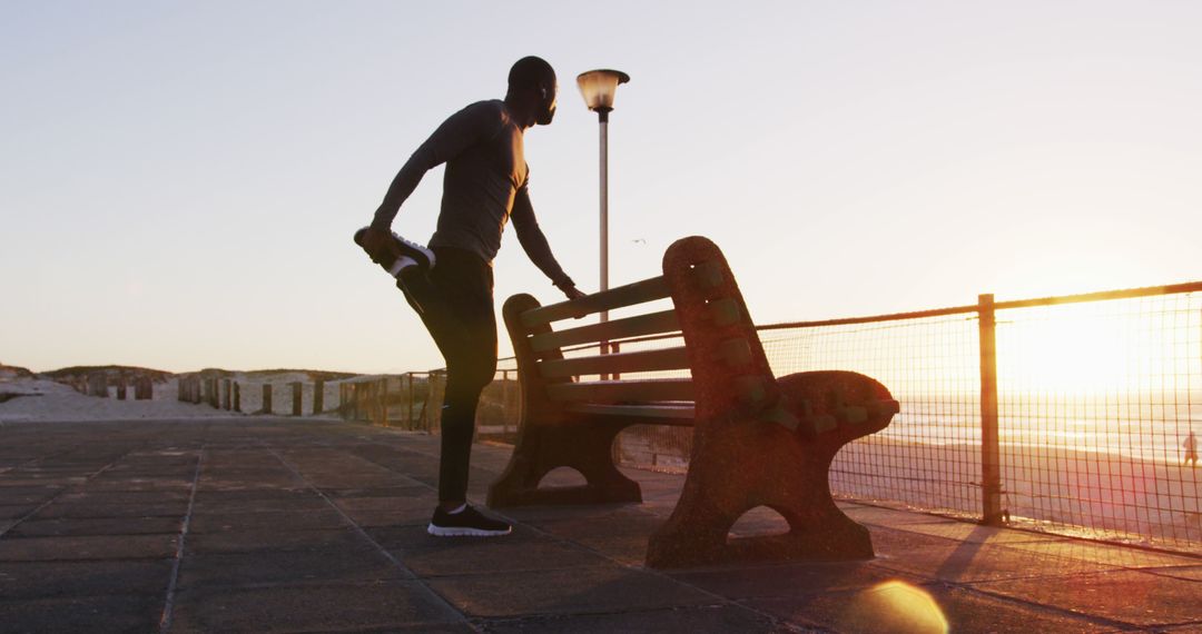 Active Man Stretching by Seaside Bench During Sunset Routine