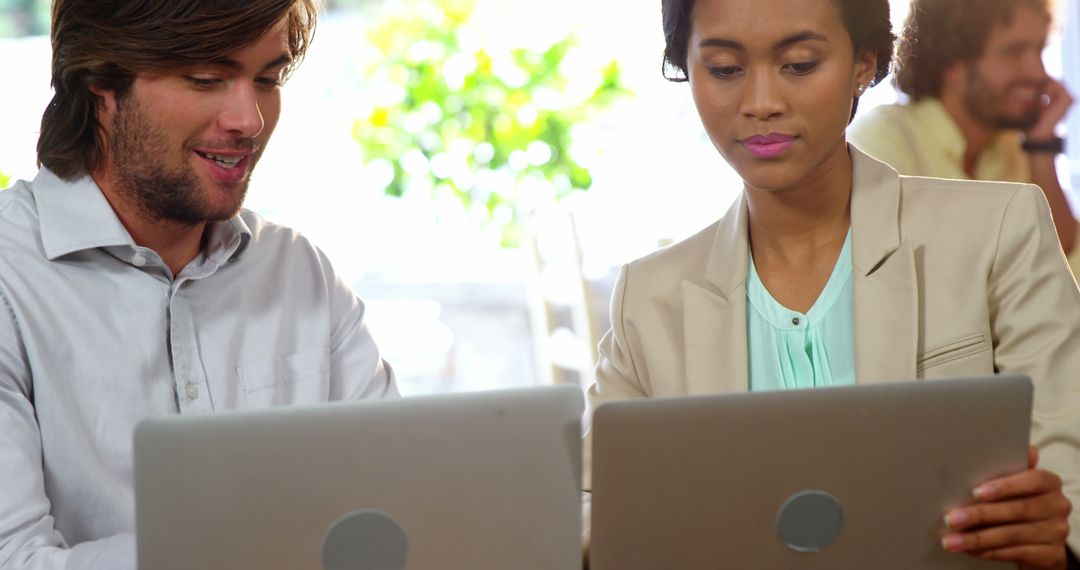Diverse Colleagues Collaborating on Laptops in Bright Cafe
