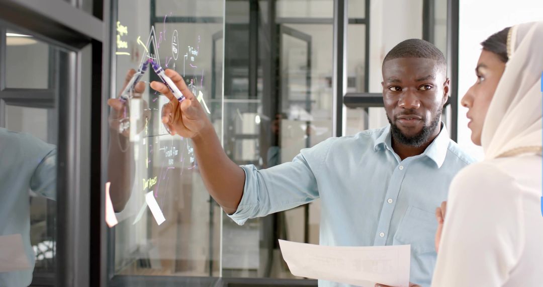 Coworkers Collaborating at Transparent Whiteboard in Modern Office