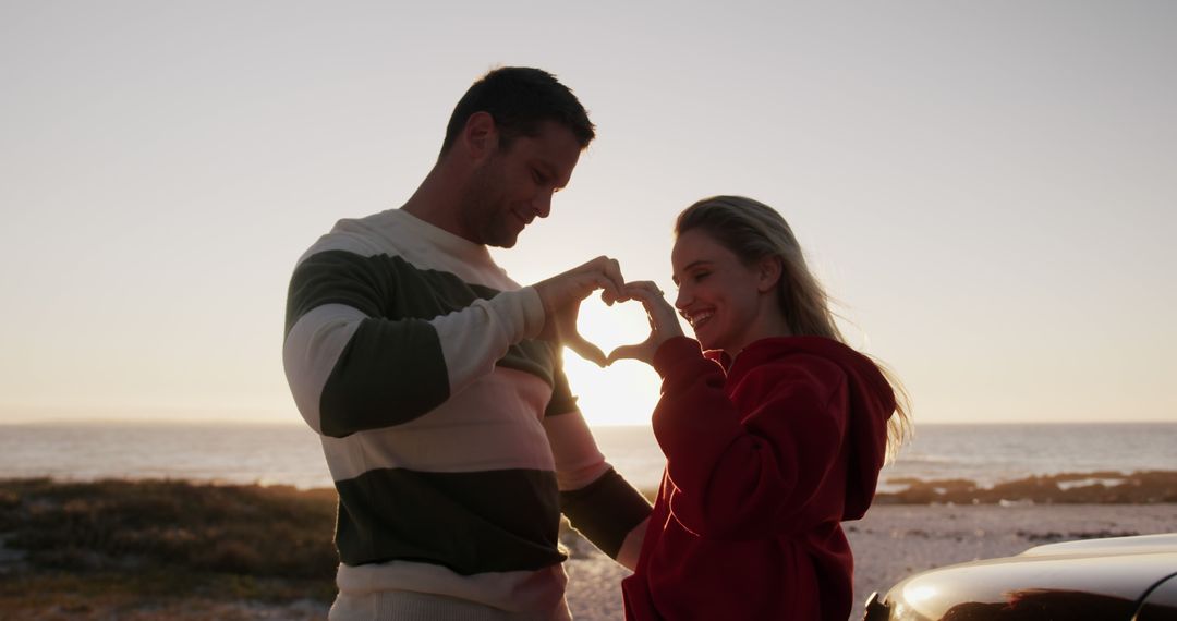 Romantic Couple Creating Heart Shape with Hands at Sunset Beach - Free Images, Stock Photos and Pictures on Pikwizard.com