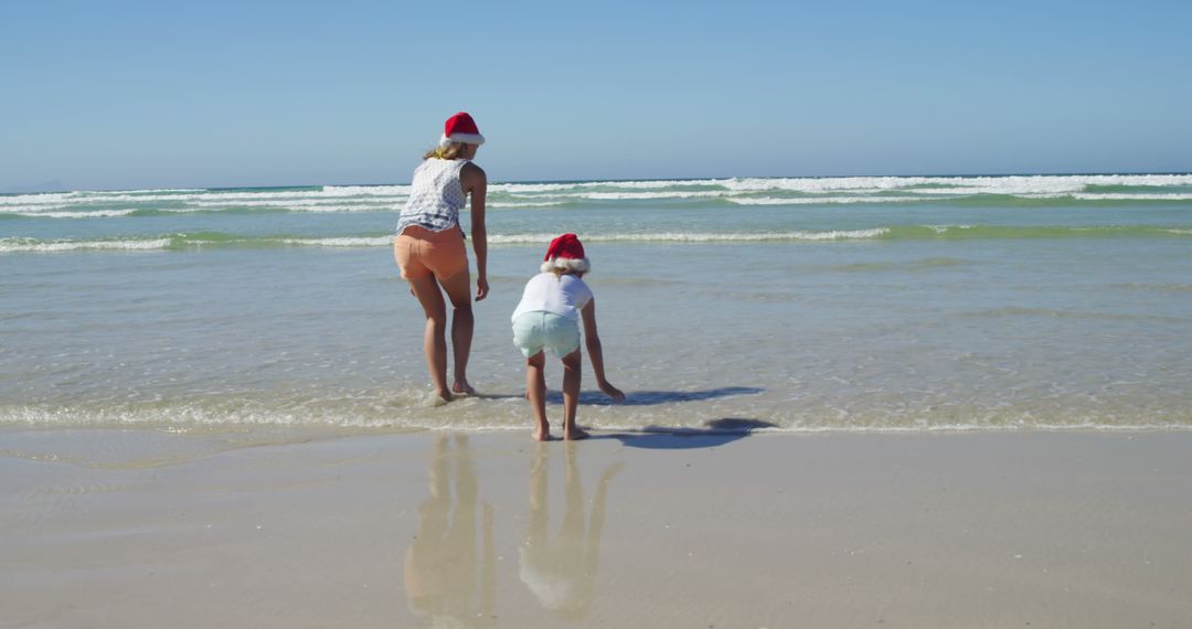 Mother and Child Wearing Santa Hats on Beach during Christmas Holiday - Free Images, Stock Photos and Pictures on Pikwizard.com