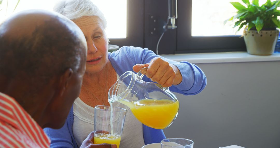 Senior Woman Pouring Fresh Orange Juice for Elderly Friend - Free Images, Stock Photos and Pictures on Pikwizard.com