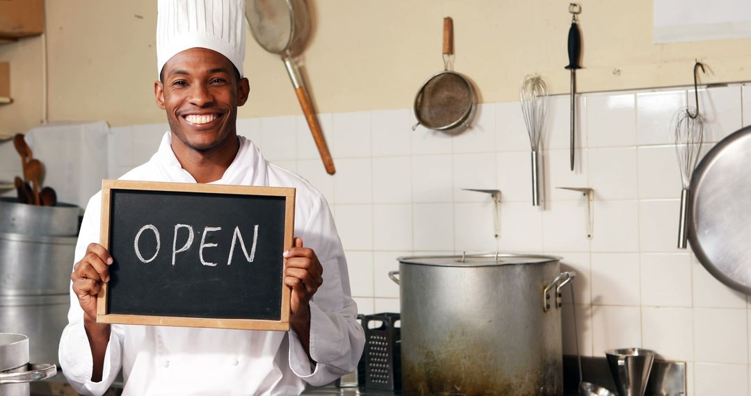 Smiling Chef Holding Open Sign in Restaurant Kitchen - Free Images, Stock Photos and Pictures on Pikwizard.com