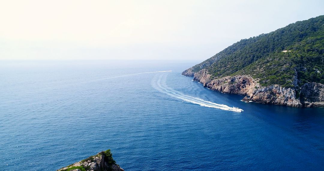 Boats Traveling Across Ocean Near Rocky Hillside - Free Images, Stock Photos and Pictures on Pikwizard.com