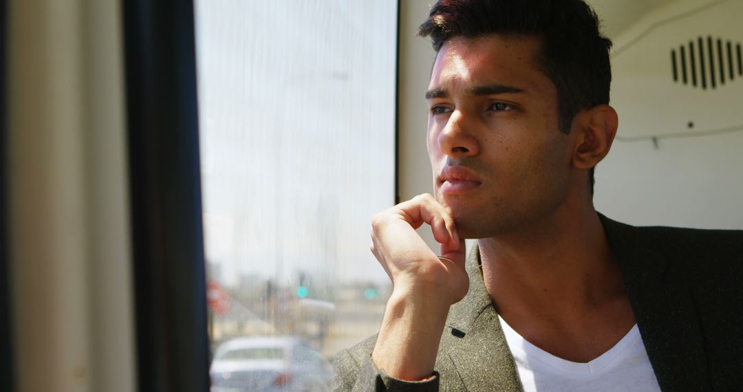 Young man thinking while gazing out train window - Free Images, Stock Photos and Pictures on Pikwizard.com