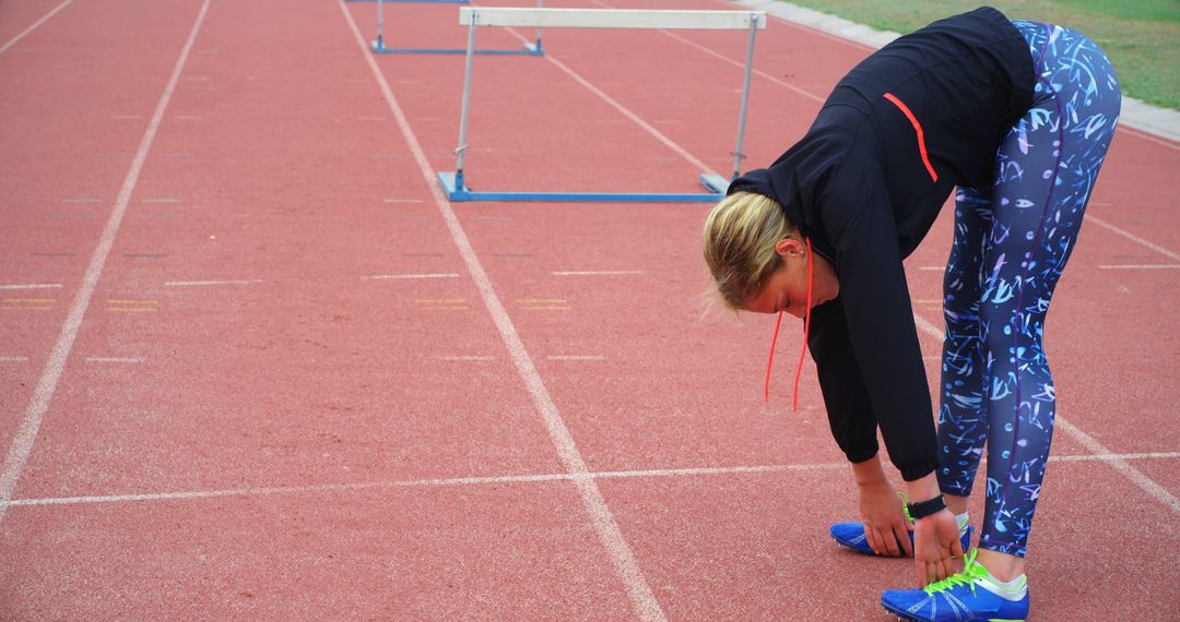 Female Runner Stretching on Track Before Hurdle Training - Free Images, Stock Photos and Pictures on Pikwizard.com