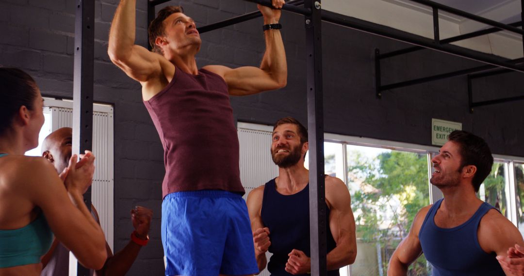 Men performing pull-up exercise while friends applauding him in gym - Free Images, Stock Photos and Pictures on Pikwizard.com