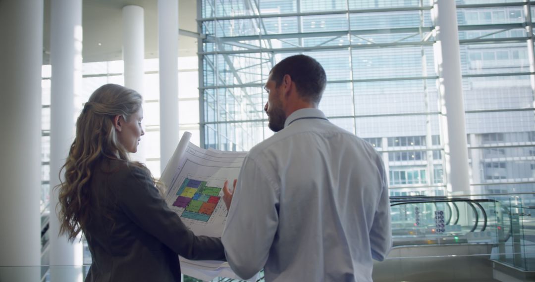 Architects Discussing Building Plans in Modern Office Atrium - Free Images, Stock Photos and Pictures on Pikwizard.com