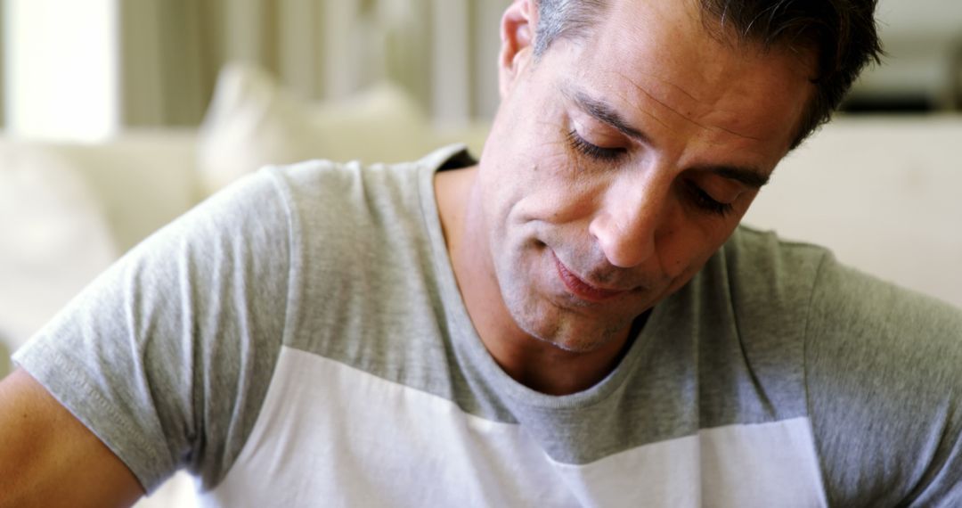 Middle-Aged Man in Grey T-Shirt Reflects Deep in Thought Indoors - Free Images, Stock Photos and Pictures on Pikwizard.com