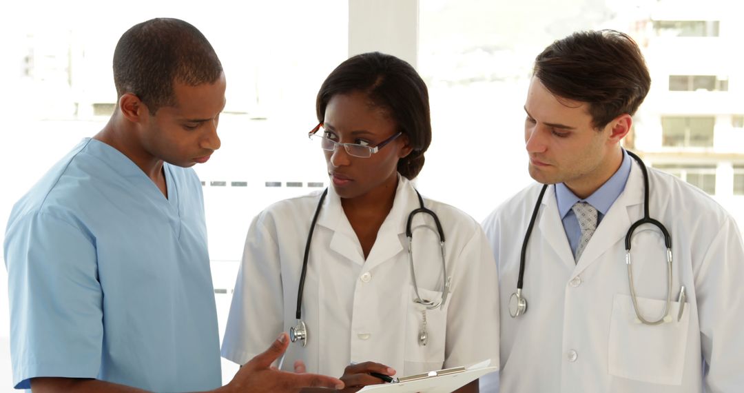 Medical Team Discussing Patient Records in Hospital Corridor - Free Images, Stock Photos and Pictures on Pikwizard.com