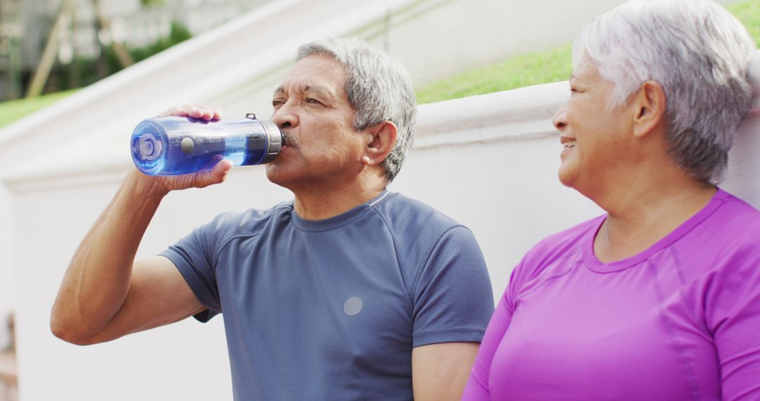 Happy Senior Couple Staying Hydrated Outdoors Wearing Athletic Clothing - Free Images, Stock Photos and Pictures on Pikwizard.com