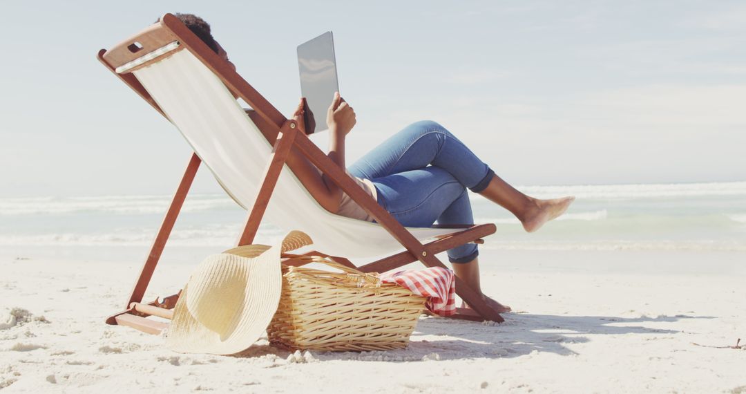 African american woman with tablet lying in hammock on sunny beach - Free Images, Stock Photos and Pictures on Pikwizard.com